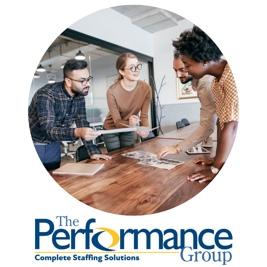 People looking at data at a table with The Performance Group logo under them.